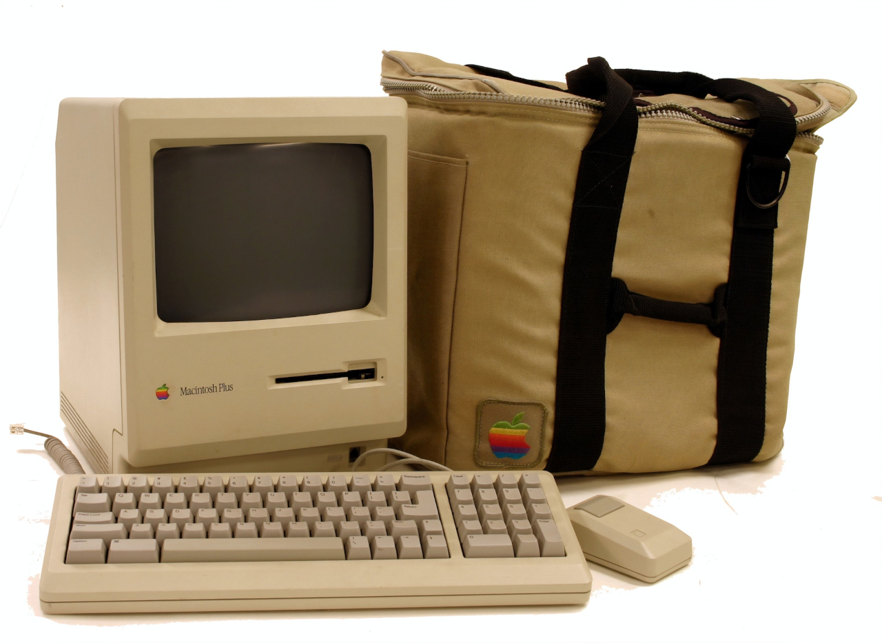 A picture of a Classic Macintosh Plus, complete with keyboard, mouse and carrying bag.