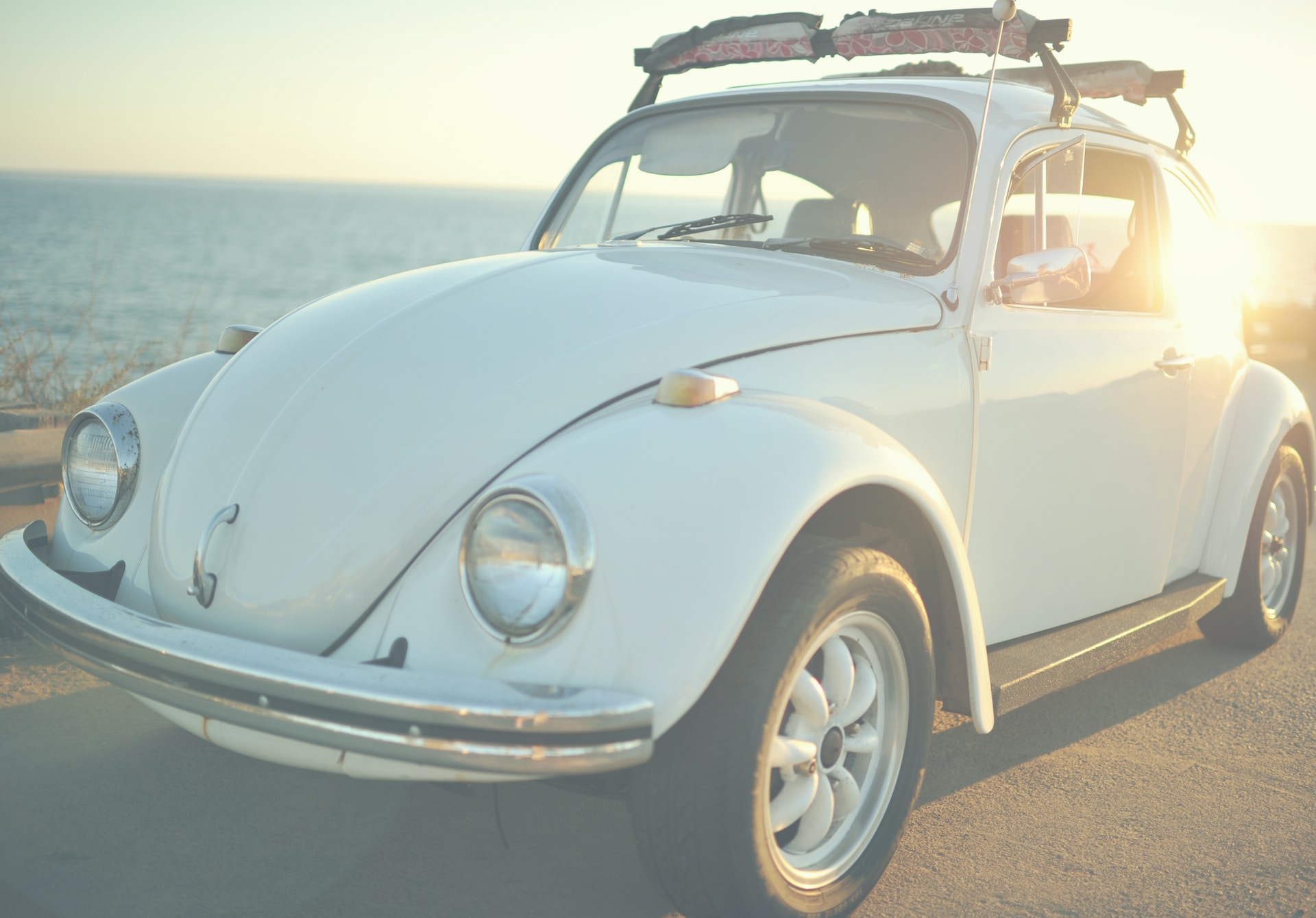 a Picture of a vintage white Volkswagen  Beetle driving.